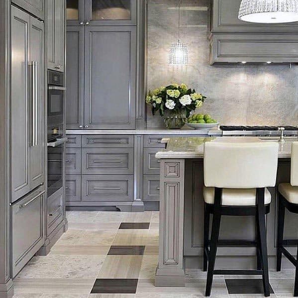 Elegant grey kitchen with paneled cabinets, marble countertops, and plush bar stools.
