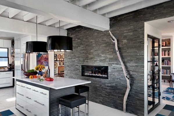 Contemporary kitchen with a dark stacked stone fireplace, sleek island, and bold modern accents