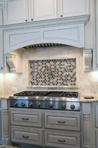 Classic kitchen with detailed cabinetry, a stone backsplash featuring a decorative tile inlay above the stove, and elegant lighting