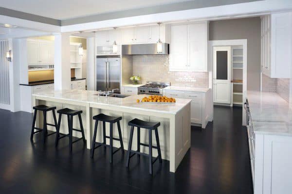 Modern kitchen with white cabinets, stainless steel appliances, two spacious islands, and black barstools