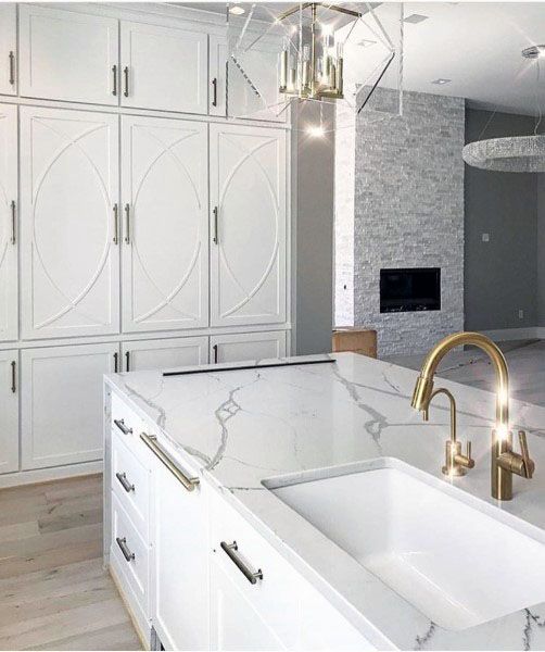 large kitchen with white cabinets marble countertops and gold accents 