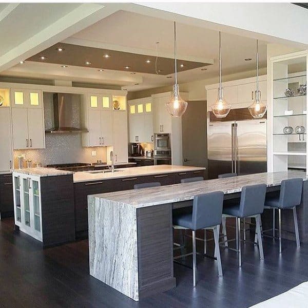 Modern kitchen with dark floors, light cabinets, a stone countertop island, pendant lights, and stainless steel appliances