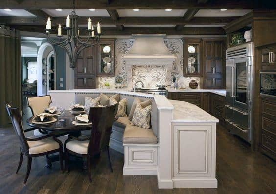 Luxurious kitchen with dark wood cabinets, a marble island, and a cozy nook featuring a round dining table and chandelier