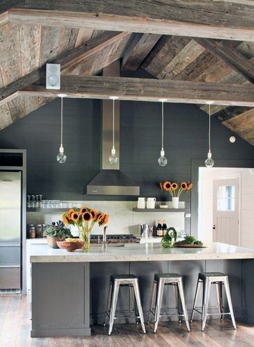 Rustic kitchen featuring wooden beams, a sunflower-adorned island, bar stools, and hanging pendant lights