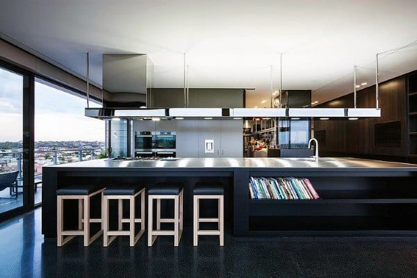 Modern kitchen with sleek island, bar stools, built-in oven, and expansive windows offering a city view
