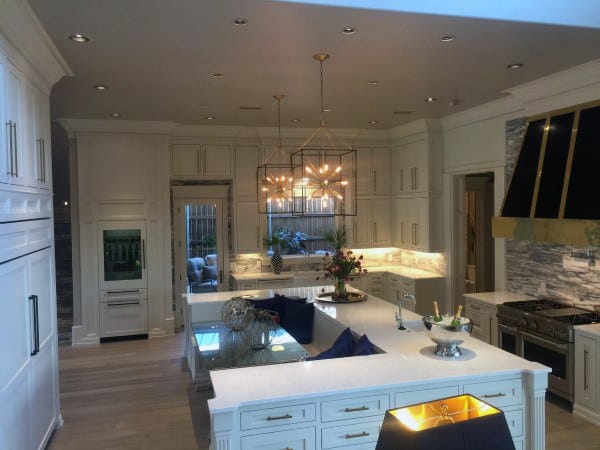 Modern kitchen featuring a large island, white cabinets, a stylish chandelier, and sleek stainless steel appliances