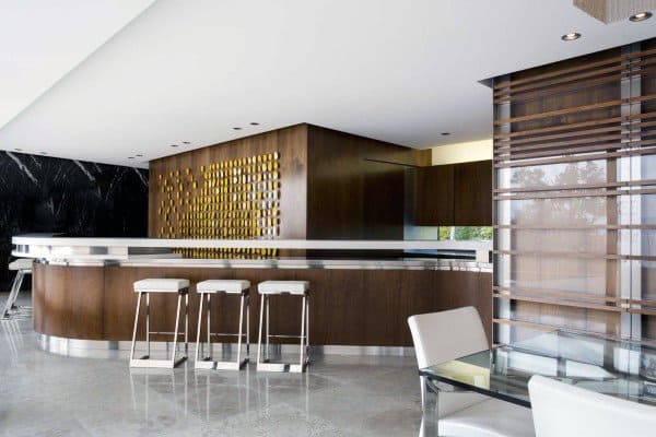 Modern kitchen with sleek wooden cabinets, a glossy island with bar stools, and abstract gold island accents