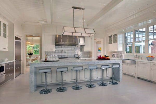 Modern kitchen with a spacious marble island, five bar stools, stainless steel appliances, and bright lighting