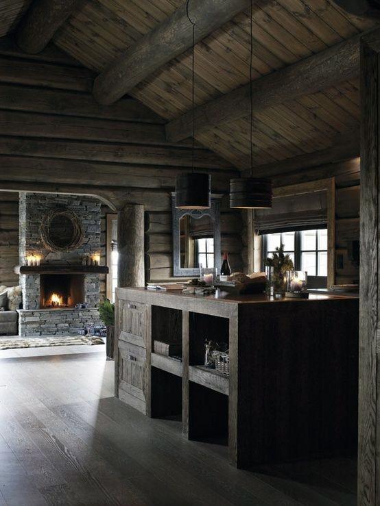 Rustic log cabin kitchen with wooden beams, stone fireplace, and warm ambient lighting.