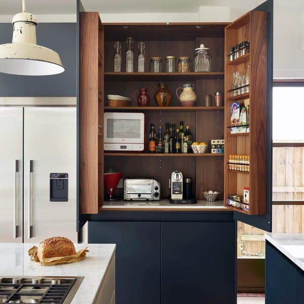 Compact pantry with wooden shelves, small appliances, and built-in spice racks.