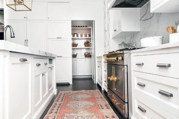 Elegant white kitchen with brass stove accents and a walk-in pantry at the back.
