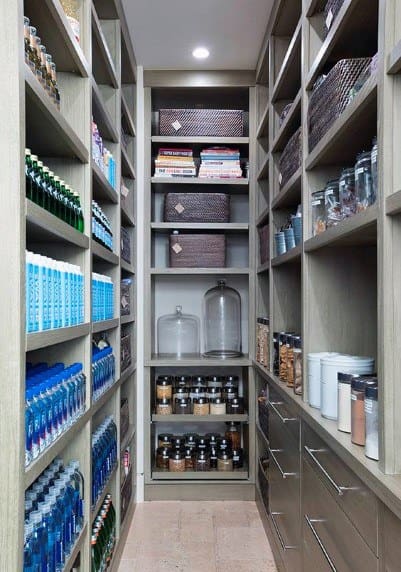 Narrow pantry with sleek wood shelving, labeled jars, woven baskets, and organized beverage storage.