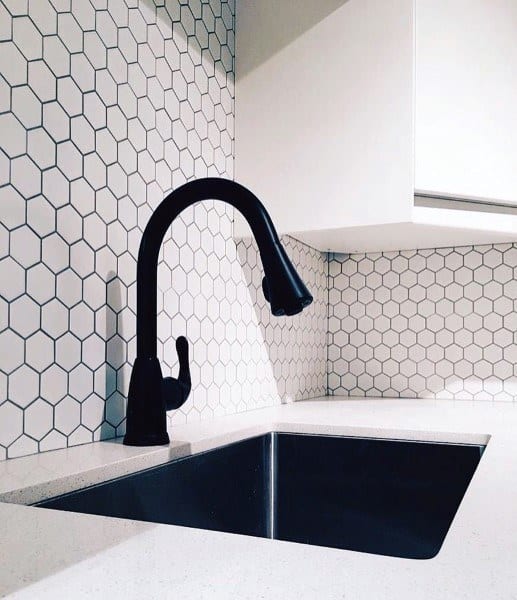 White hexagon tile backsplash with black faucet and undermount sink.