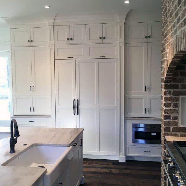 A beautiful kitchen with white cabinetry, marble countertops, and elegant crown molding, creating a clean, sophisticated space with modern appliances