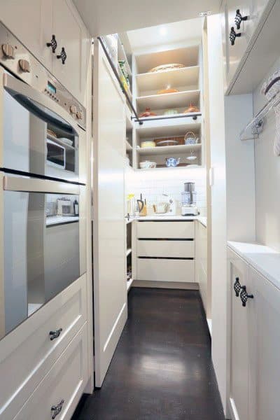 Compact pantry with built-in shelves, soft lighting, and sleek white cabinetry for a modern look.