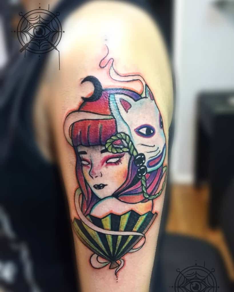 Colorful upper arm tattoo of a mystical Geisha with a kitsune mask, red moon, flowing smoke, and a decorative fan in a neo-traditional style.
