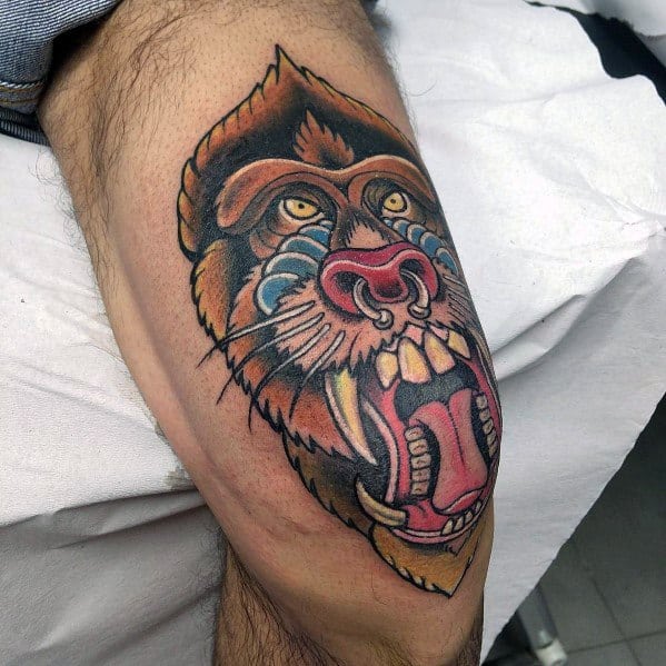 Neo-traditional baboon tattoo with bold outlines, vivid colors, and a fierce expression, featuring intricate shading for a dynamic leg design.