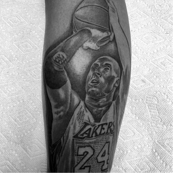 A black and white tattoo of Kobe Bryant in action, wearing his Lakers jersey with number 24, capturing his focused expression while taking a shot.