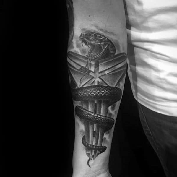 A detailed black and white tattoo featuring a coiled snake intertwined with the iconic Kobe Bryant "Mamba" logo, symbolizing strength and resilience.