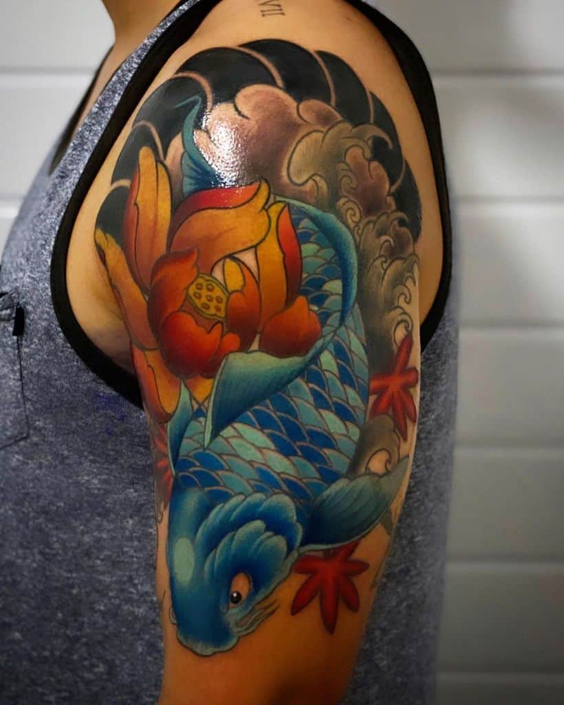 Colorful koi fish tattoo on upper arm with floral and wave elements