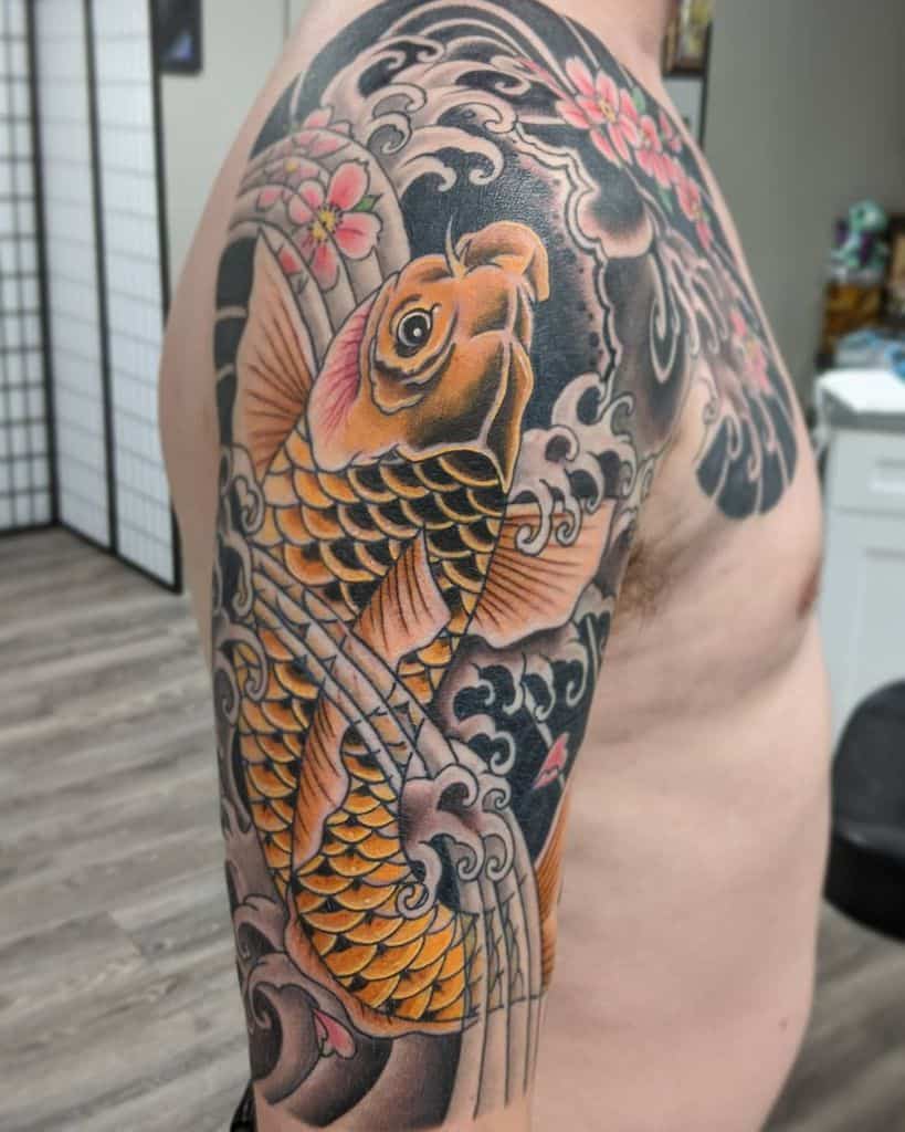 Colorful koi fish tattoo with waves and cherry blossoms on a man's upper arm and shoulder