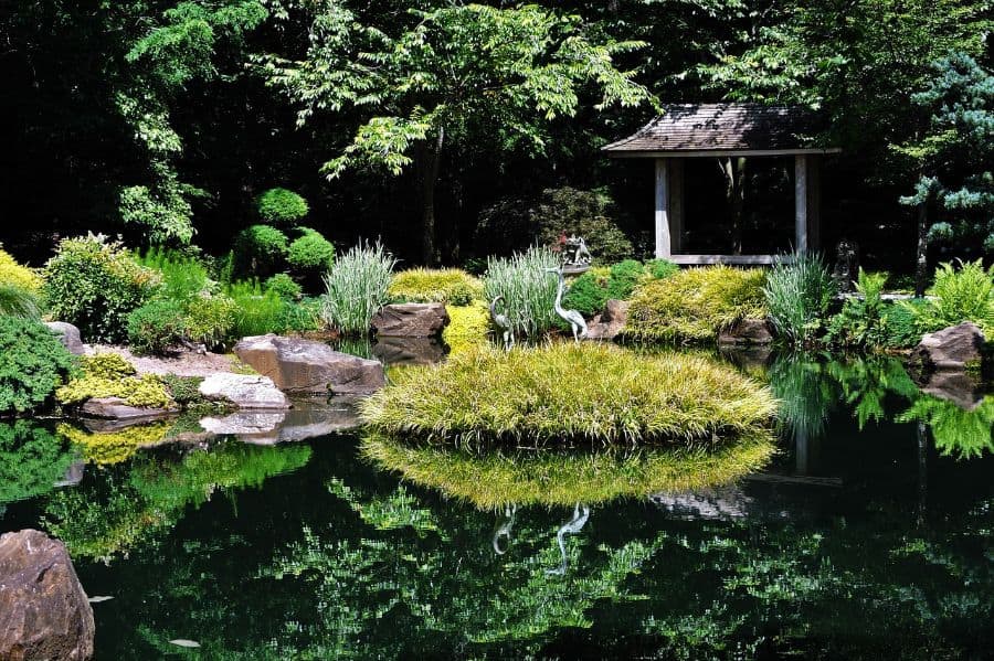 large garden with pond and small island with bird statues 