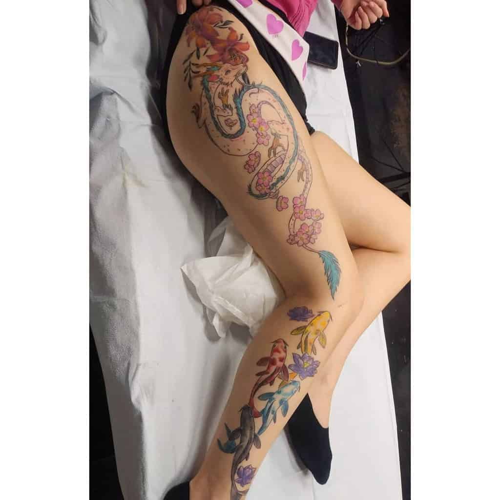 Stunning tattoo of Haku in dragon form from Spirited Away, surrounded by cherry blossoms, koi fish, and floral details