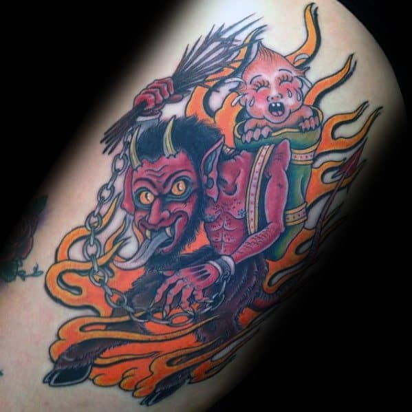 Bright Krampus tattoo with orange flames, showing the red demon holding chains and birch sticks, carrying a crying child on his back.