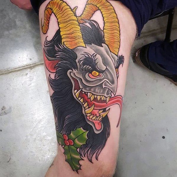 Colorful Krampus tattoo on leg featuring a snarling grey face, twisted yellow horns, long red tongue, sharp fangs, and holly leaves.