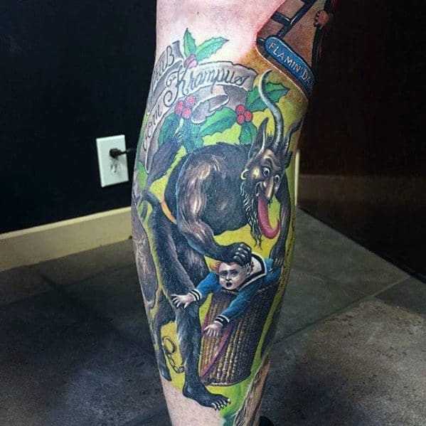 Colorful Krampus tattoo on calf showing the beast dragging a child into a basket, surrounded by holly leaves and festive lettering.