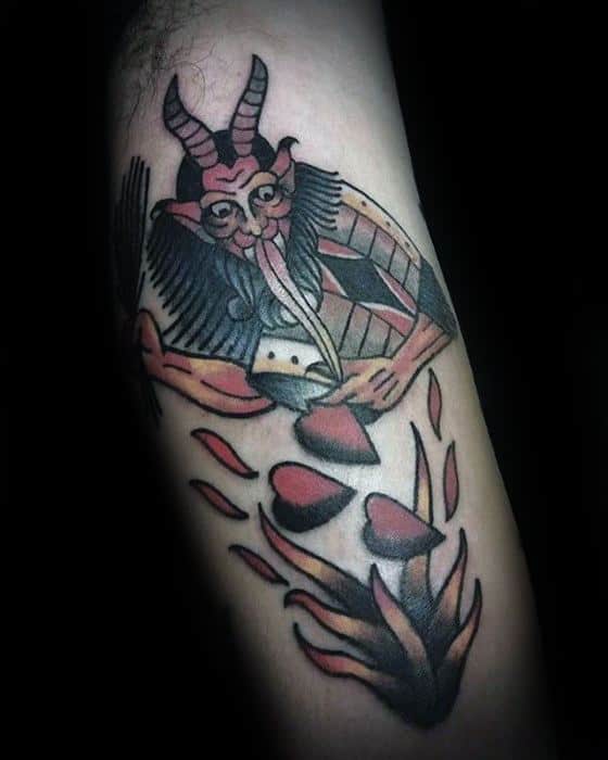 Stylized Krampus tattoo with a horned figure in a cloak tossing red hearts into flames, done in a bold, neo-traditional style.