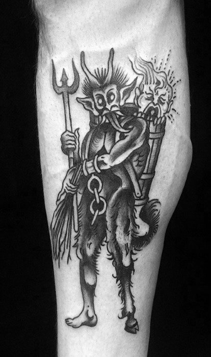 Black and grey Krampus tattoo showing the creature holding a pitchfork and birch branches, with a crying child in a basket on his back.