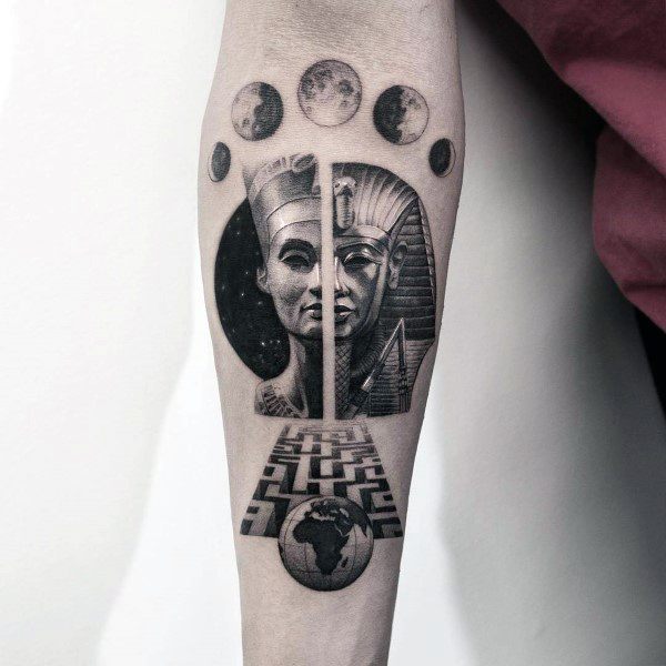 Surreal black and grey tattoo on a man's forearm, featuring split Egyptian pharaoh faces, a 3D labyrinth path, moon phases, and Earth below.