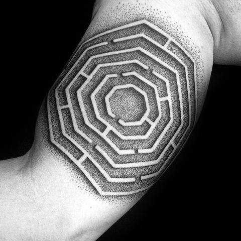Octagonal labyrinth tattoo on a man's inner arm, featuring bold geometric lines with intricate dot shading for depth and contrast.