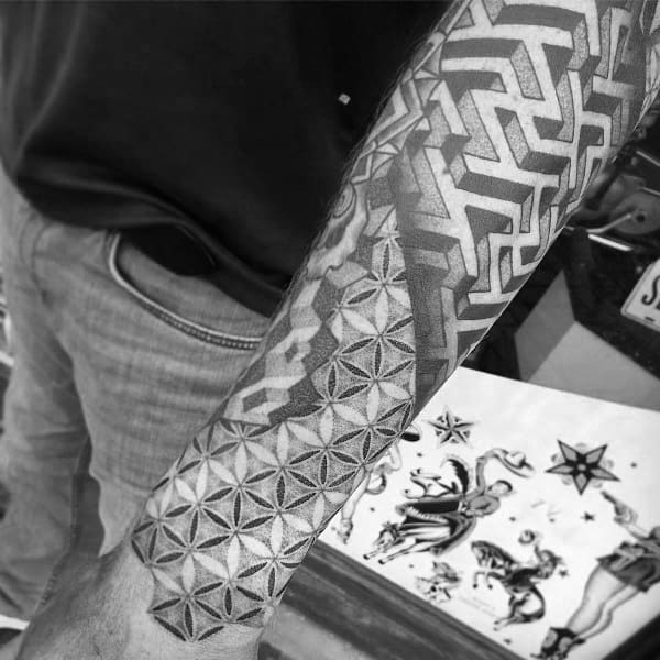 Geometric full-sleeve tattoo on a man's arm, featuring an intricate labyrinth pattern blending into a floral-like tessellation with shading effects.