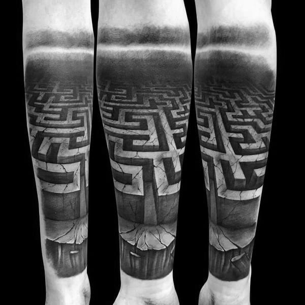 Realistic black and grey labyrinth tattoo on a man's forearm, featuring a 3D maze with deep shading, cracks, and a dramatic perspective effect.
