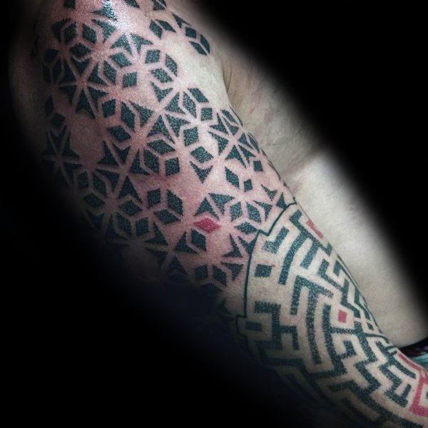 Geometric blackwork tattoo on a man's arm, featuring an intricate maze pattern transitioning into a tessellated design with bold black shapes.