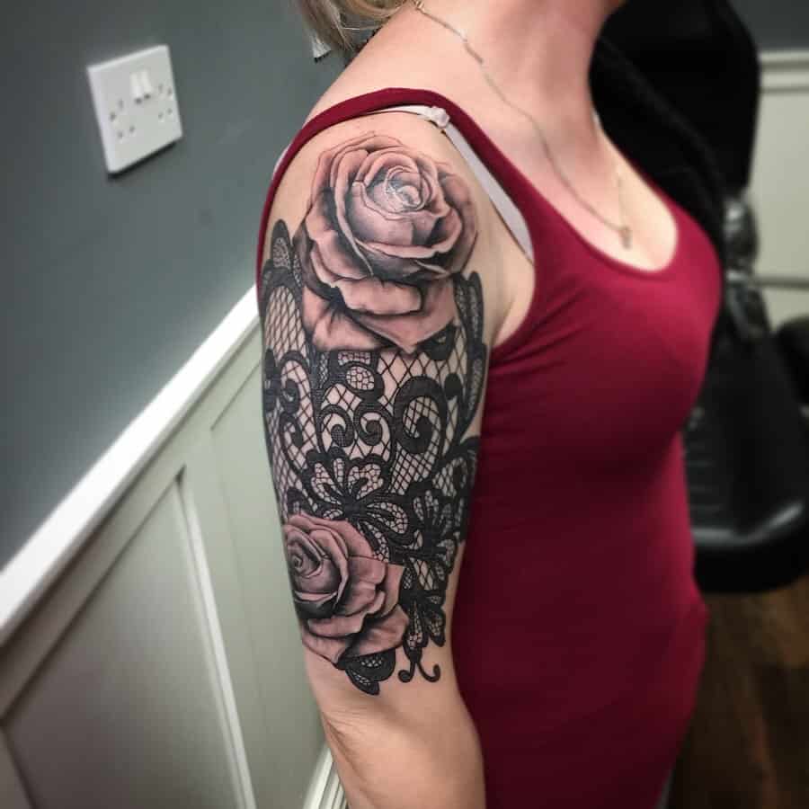 Black and grey half-sleeve tattoo featuring realistic roses intertwined with intricate lace patterns and ornamental filigree details.