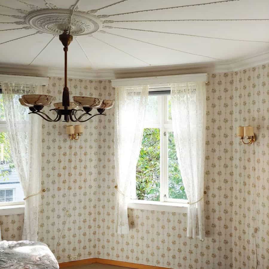Vintage bedroom with lace curtains, ornate ceiling design, and antique chandelier.