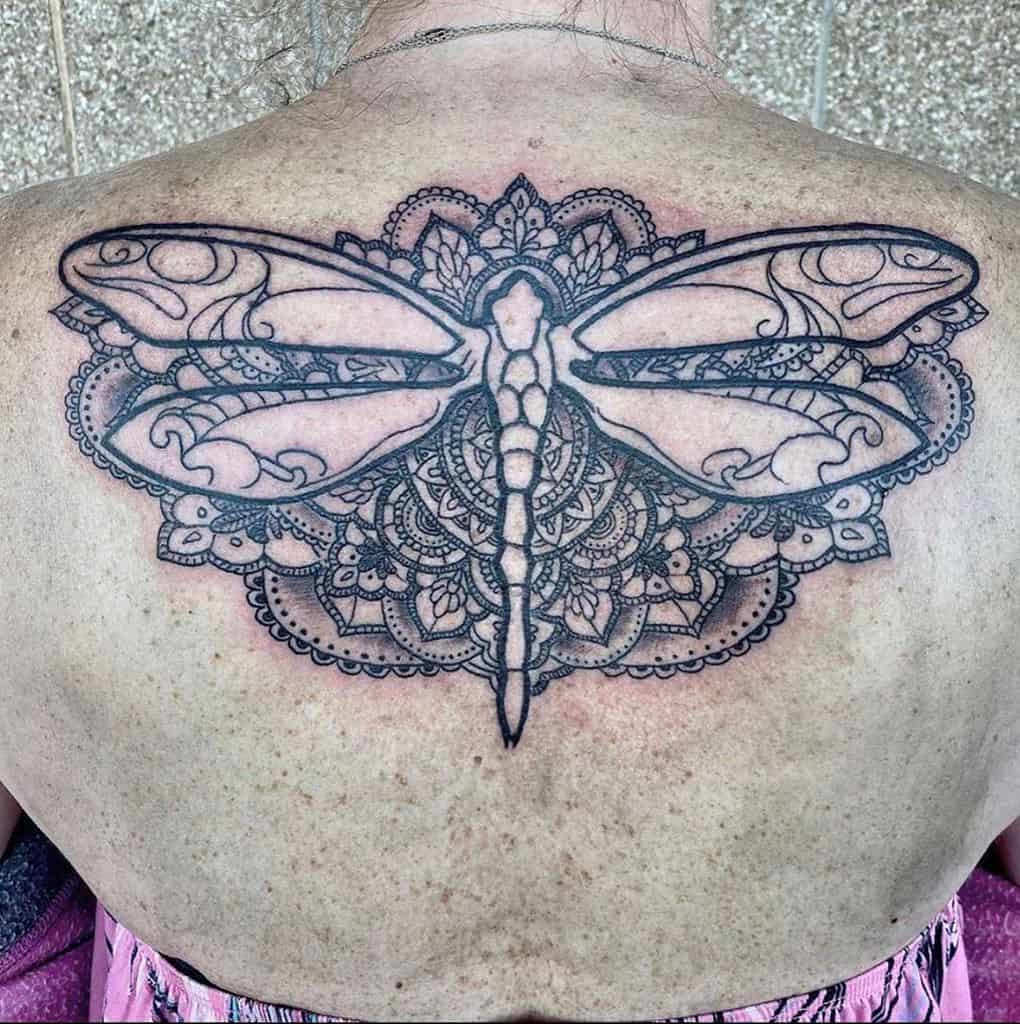 Elegant back tattoo featuring a detailed dragonfly with ornamental lace and mandala patterns, blending nature-inspired and intricate designs.