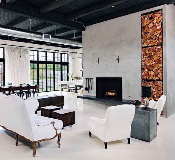 Industrial-style living space with a large concrete fireplace and vertical firewood storage.