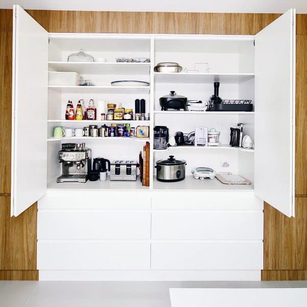Spacious white pantry with shelves holding appliances, jars, and cookware.