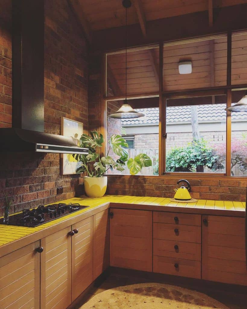 large kitchen windows wood cabinets yellow tile countertop brick wall backsplash