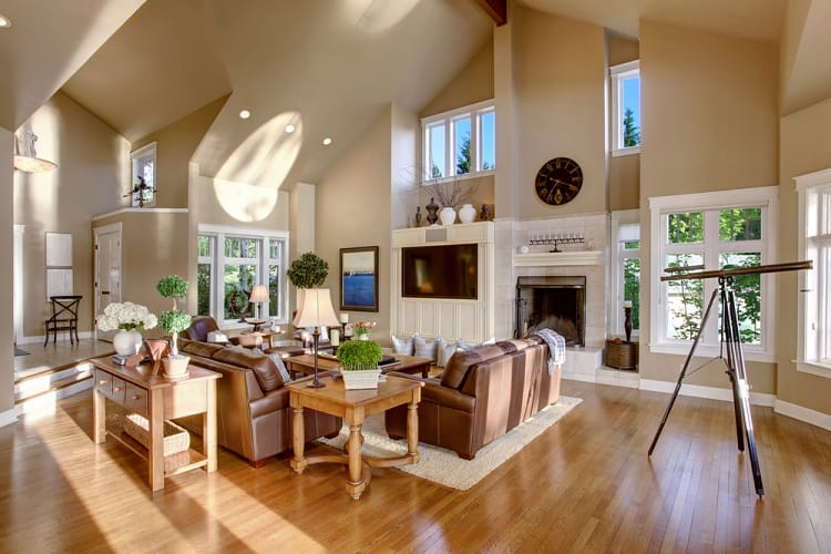 Spacious living room with high ceilings, leather sofas, a telescope by the windows, and a cozy fireplace