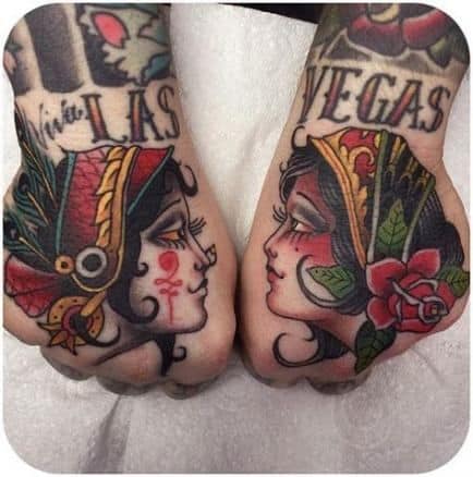 Traditional gypsy woman tattoos on both hands, facing each other with bold colors, roses, and feathered headpieces.
