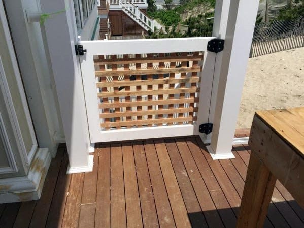 Lattice deck gate with a wooden design, overlooking a sandy area and fence