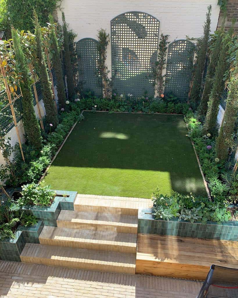 large lattice garden trellis green grass area wood deck bench