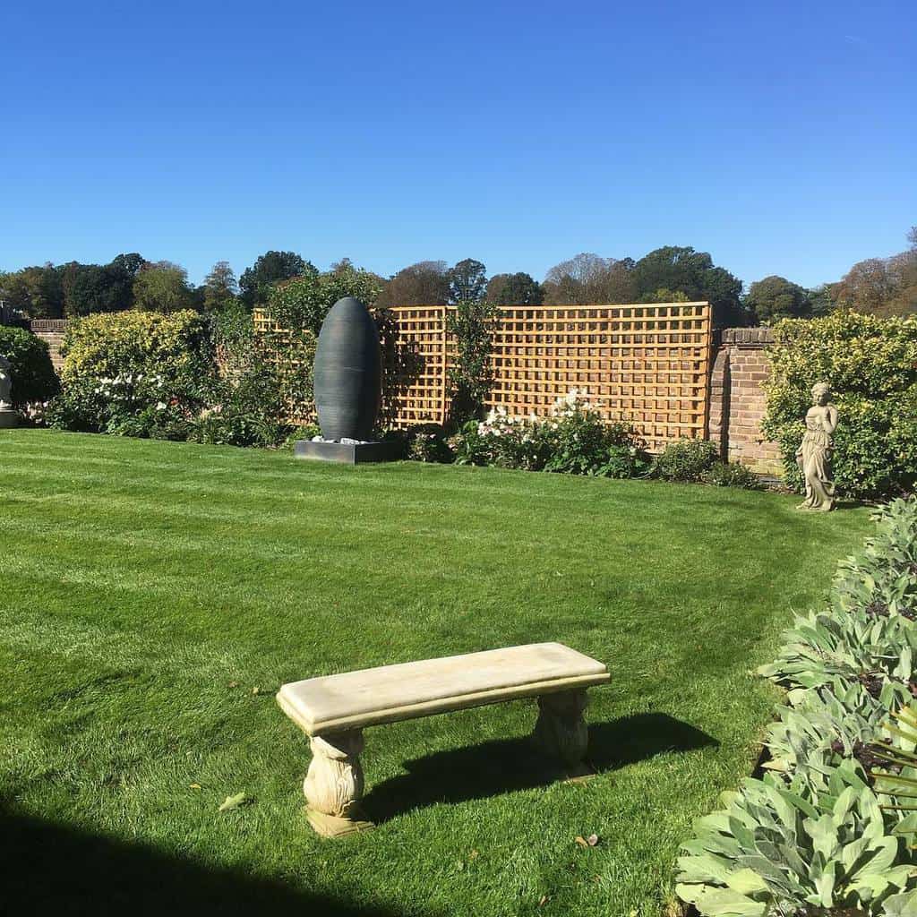 large wood lattice garden trellis brick fence stone seat and statue