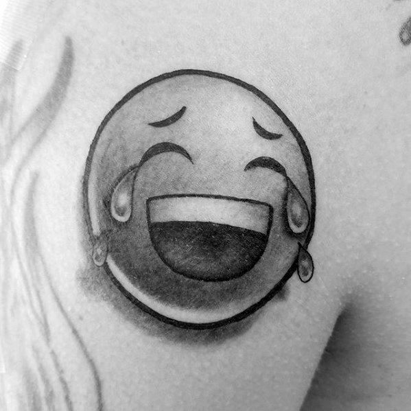 Black and white tattoo featuring a laughing crying emoji on skin