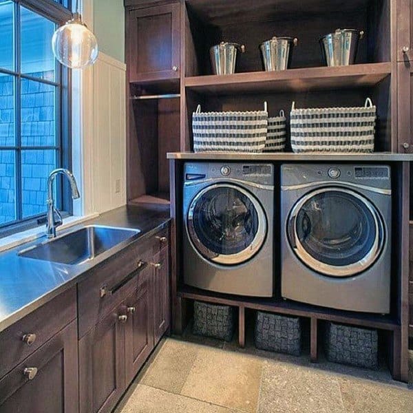 Laundry room with dark wood cabinets, stainless steel appliances, and organized shelving.